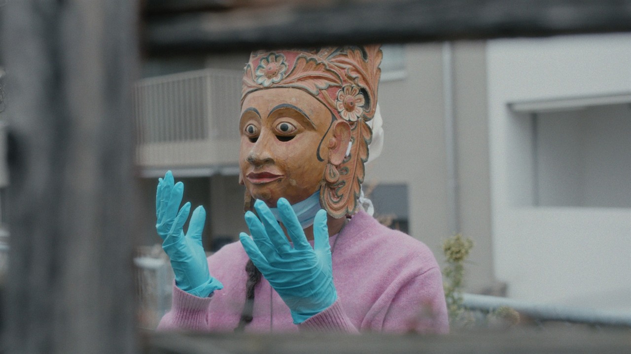 A person wearing surgical gloves and wood mask